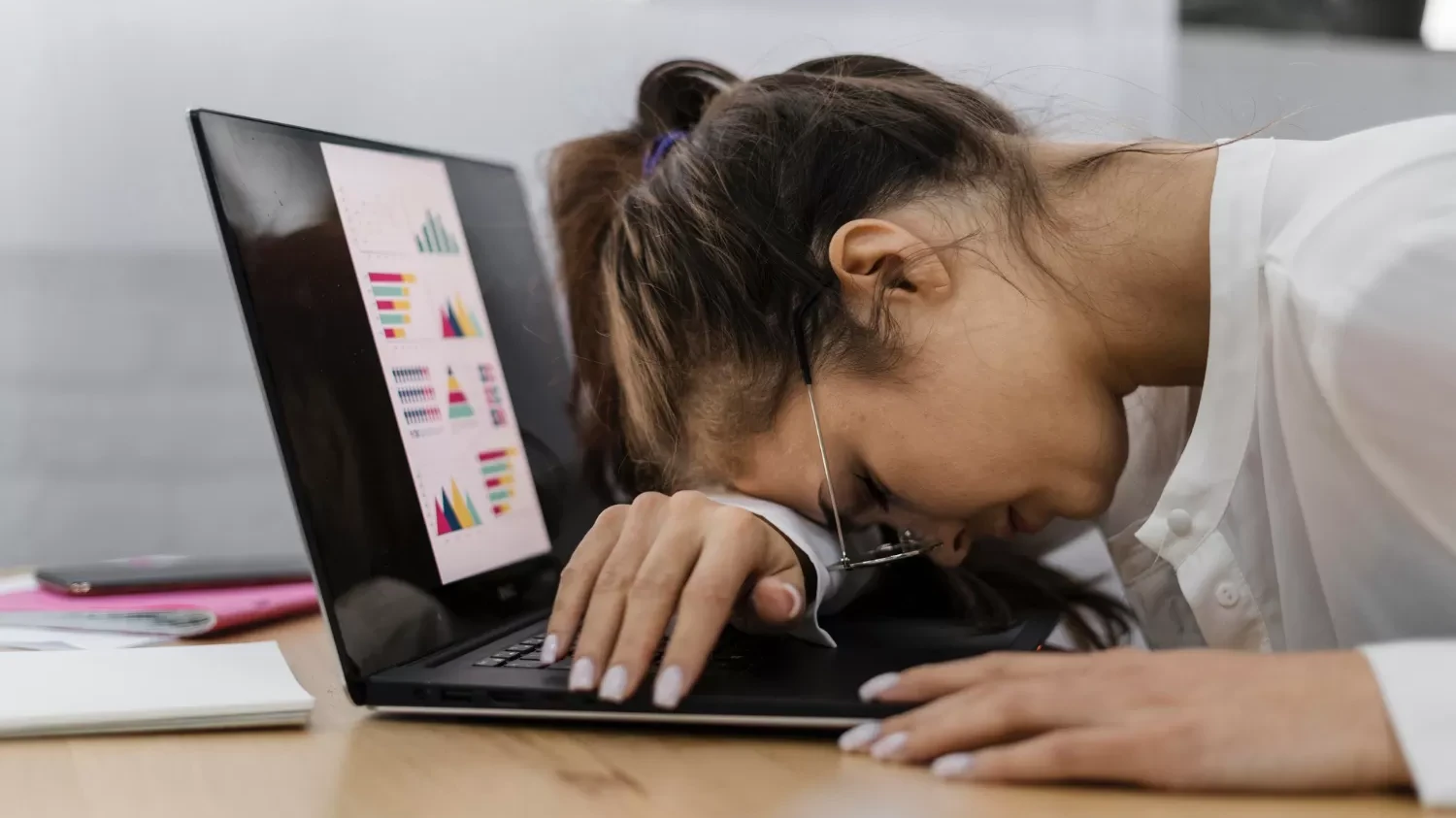 A tired woman sleeps on her laptop, her eyes on a graph discussing time blindness and coping strategies.