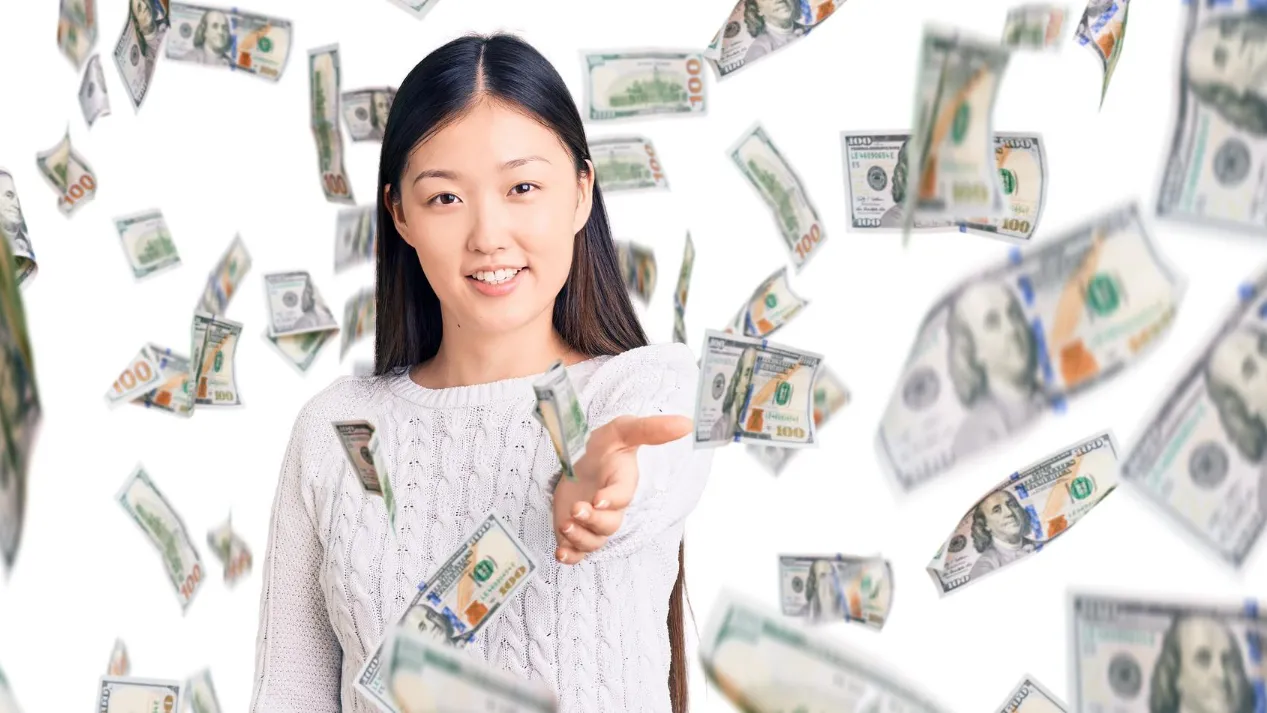 A woman confidently raises her hand in front of a stack of cash, symbolizing the importance of negotiating salary.